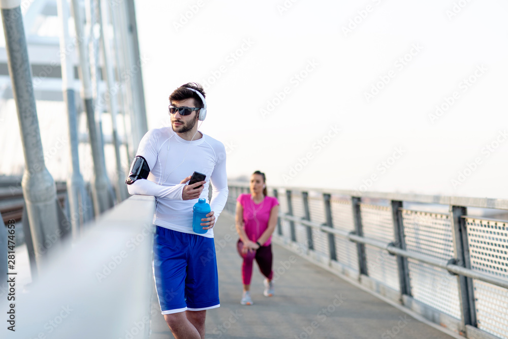 Couple exercise on the bridge at the end of day with headphones on head