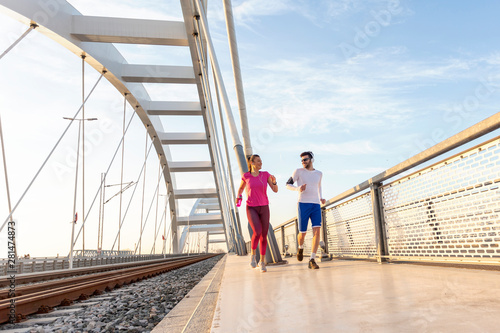 Couple exercise on the bridge at the end of day with headphones on head © pucko_ns