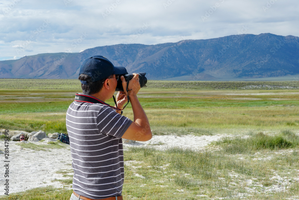 Asian man visiting and taking photo of the Wild Willy's Hot Spring in Long Valley, Mammoth Lakes, Mono County, California. USA. Natural hot springs from old volcanic activity.