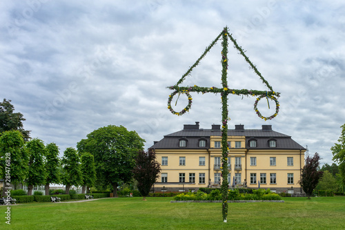 Photography Swedish holiday midsummer by raising the maypole covered in flowers and leaves