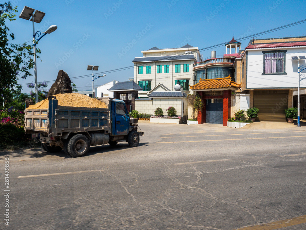 A truck with sand drives through a small village in the Countryside near Kunming in Yunnan Province (China).