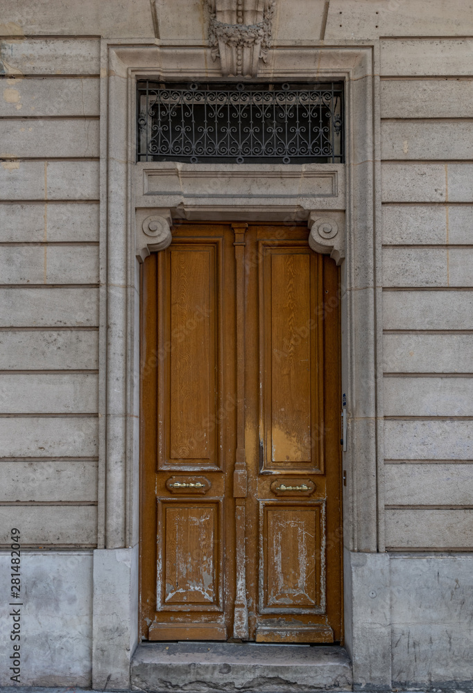 Old wooden door in wall. Shabby door entrance of old building in Paris France. Antique wooden doorway and patterned metal grid on window of stone house. Classical style architecture in Europe. Old wooden door in wall. Shabby door entrance of old building in Paris France. Antique wooden doorway and patterned metal grid on window of stone house. Classical style architecture in Europe.