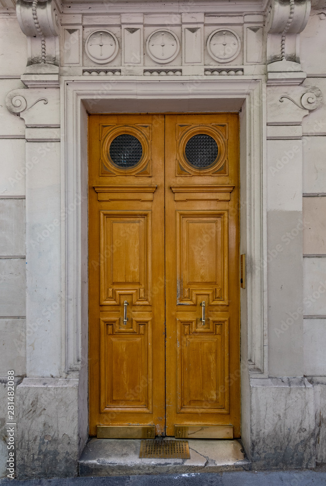 Old wooden door. Elegant old double door entrance of building in Paris France. Vintage wooden doorway and stucco fretwork wall of ancient stone house with round medallions. Ornate carving wood door. Old wooden door. Elegant old double door entrance of building in Paris France. Vintage wooden doorway and stucco fretwork wall of ancient stone house with round medallions. Ornate carving wood door.