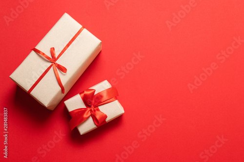 Top view of arranged wrapped christmas gift boxes with red ribbons on red tabletop