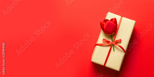 Top view of wrapped spring gift boxes with red ribbons on red table top. © Shi 