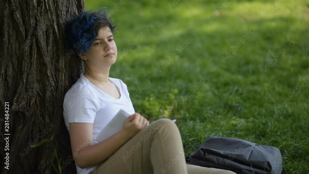 teenager in the park reading a book sitting on the grass teenager in the park reading a book sitting on the grass