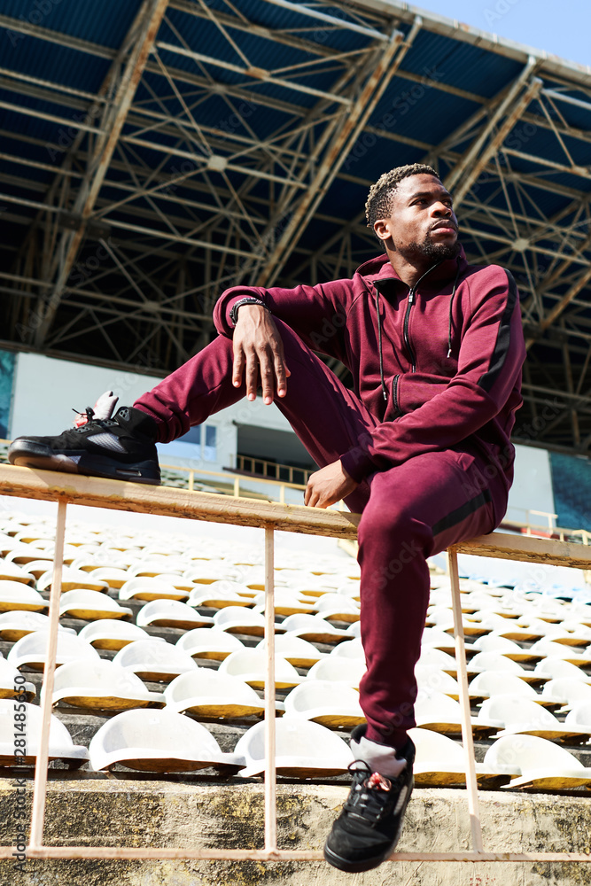Fototapeta premium Dark-skinned guy in sportswear posing on the street. Exercise in the fresh air, lifestyle, sports field, rest in time sports.