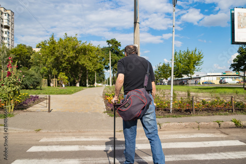 Disabled person on crutches crosses the carriageway at a crosswalk
