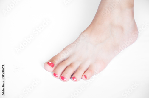 Fototapeta Naklejka Na Ścianę i Meble -  The left leg of a woman. Nails are painted red. On a white background