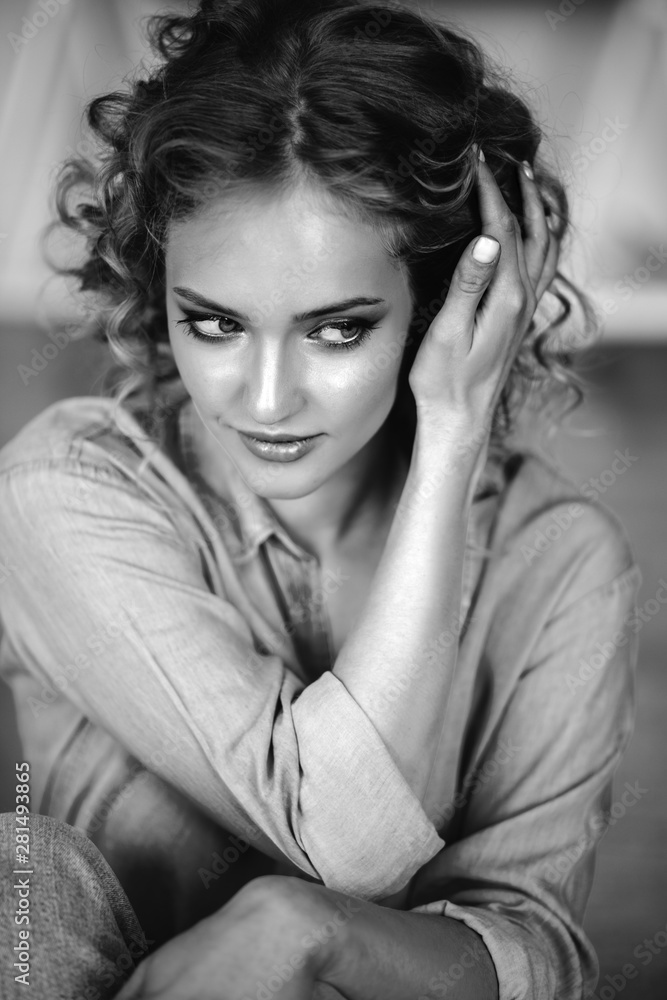 Pretty cheerful blonde young woman with curly hair and charming smile resting in her home, room with modern scandinavian interior Pretty cheerful blonde young woman with curly hair and charming smile resting in her home, room with modern scandinavian interior