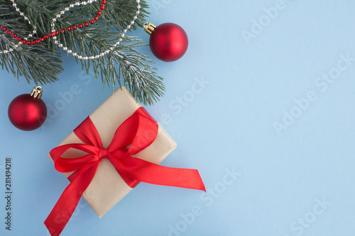 Christmas gift with red ribbon and christmas composition on the blue background. Top view. Copy space.