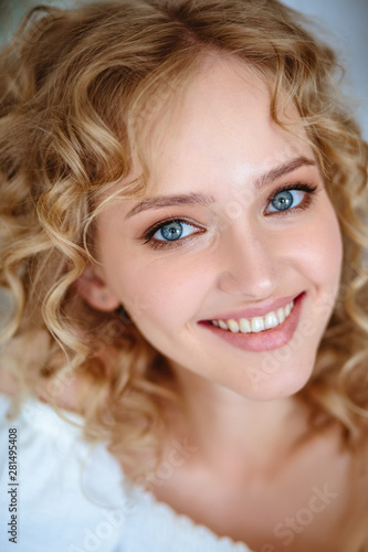 Close up portrait of blonde charming young woman with curly hair and natural makeup. Sunny morning, spa and care
