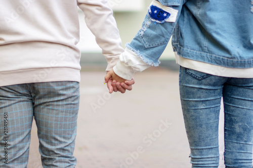 A young couple holding hands with tenderness and love in the street.