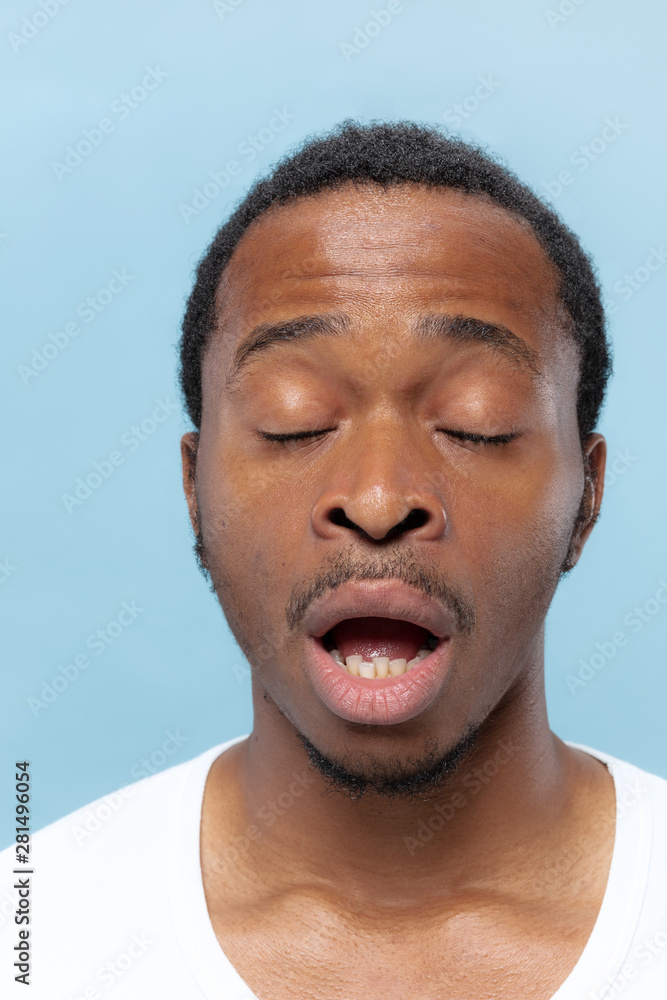 Obraz premium Close up portrait of young african-american man in white shirt on blue background. Human emotions, facial expression, ad, sales concept. A few seconds before the sneezing.