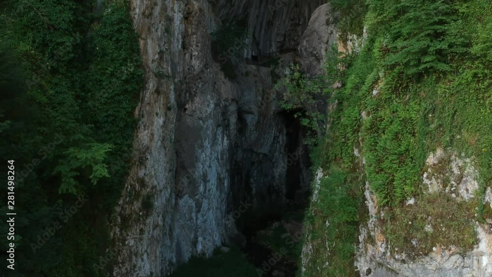 Potpec Cave pull back reveal rocky cavity in overgrown wilderness mountain rock face. Uzice, Serbia Potpec Cave pull back reveal rocky cavity in overgrown wilderness mountain rock face. Uzice, Serbia