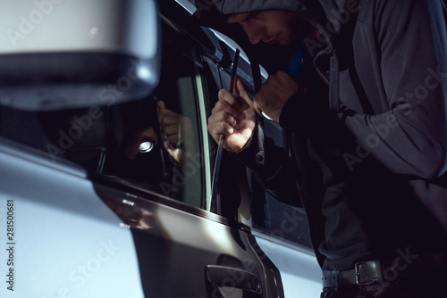 Fotografía thief intruding car with flashlight and crowbar