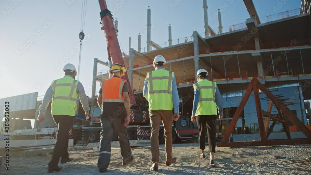 Diverse Team of Specialists Inspect Commercial, Industrial Building Construction Site. Real Estate Project with Civil Engineer, Investor and Worker. In the Background Crane Skyscraper Formwork Frames 