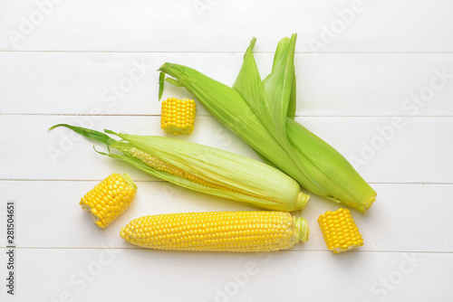 Fresh corn cobs on white wooden background