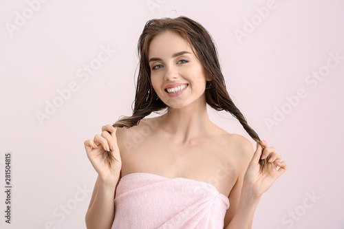 Beautiful young woman after washing hair against light color background