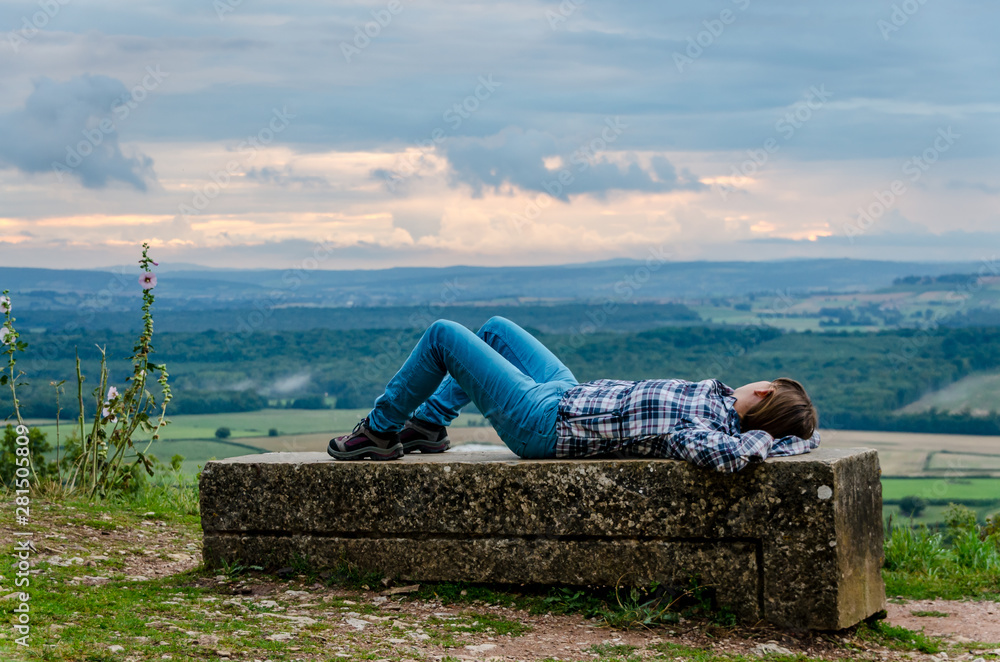 Young woman lying on a stone with background landscape Young woman lying on a stone with background landscape