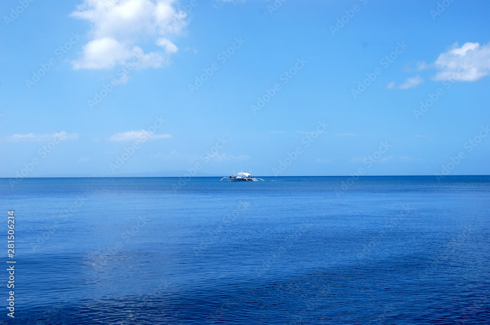 Traditional boat fishing in the middle of the blue ocean, under a clear sky