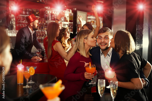 Two women kissing man at nightclub