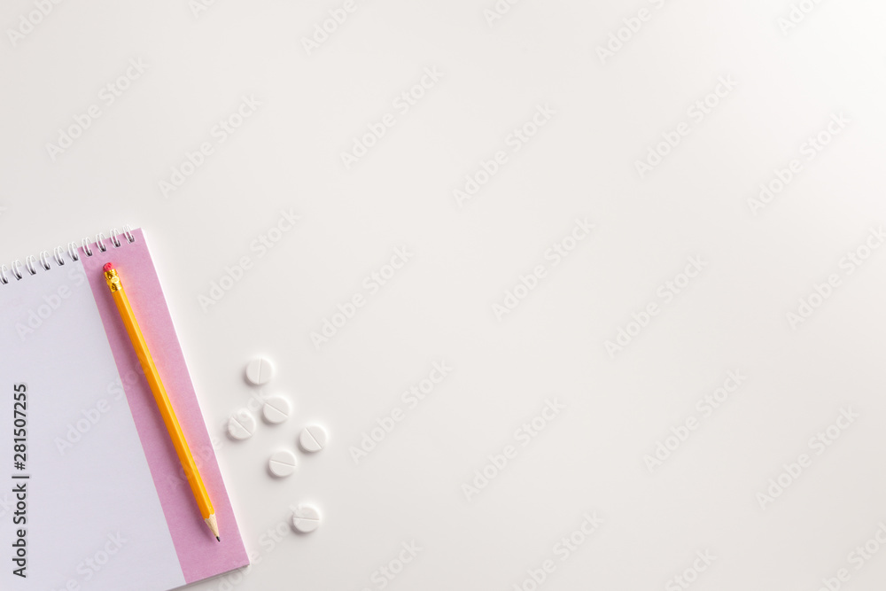 Notepad, pencil and pills on white background. Medical concept. Flat lay. Notepad, pencil and pills on white background. Medical concept. Flat lay.