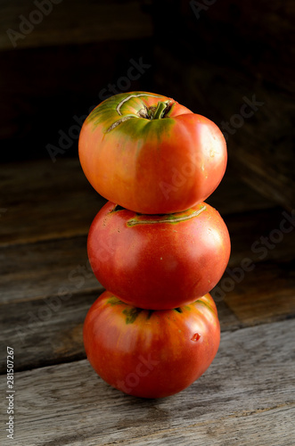 Ripe red tomatoes stacked in an orderly manner on an old rustic table.