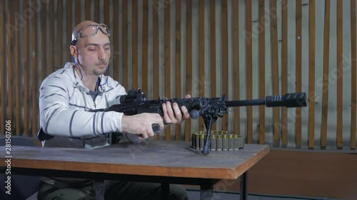 A man in a shooting range loading a carbine of the twelfth caliber and shoots at a target. The cartridge cases fly right into the camera! Shooting training at the shooting range.