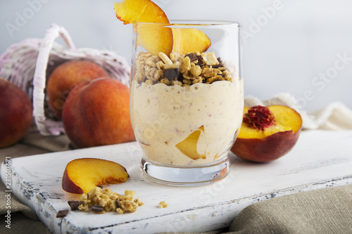 Healthy peach yogurt in a glass on a rustic white wood background