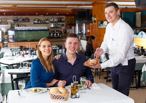 Waiter serving dishes to couple
