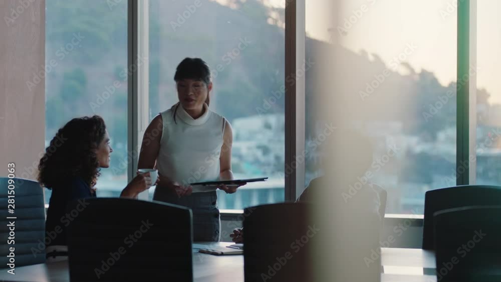 business people working late asian team leader woman meeting with colleagues discussing project manager sharing ideas on tablet computer group of executives brainstorming in office at sunset