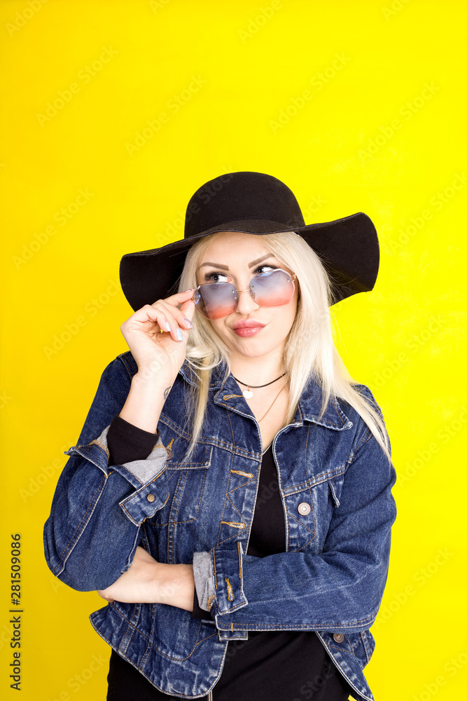 beautiful blonde girl in a hat and a denim jacket is smiling on a yellow background beautiful blonde girl in a hat and a denim jacket is smiling on a yellow background
