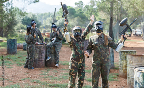 Portrait of cheerful female paintball players with marker guns outdoors
