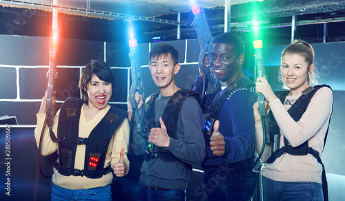 Glad group having fun on dark lasertag arena