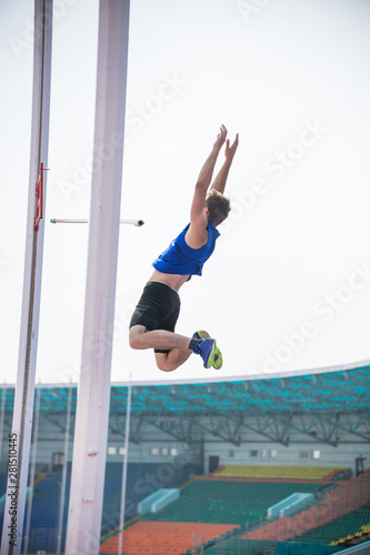 Pole vault - a young athletic man falling down on the mat after jumping over the bar