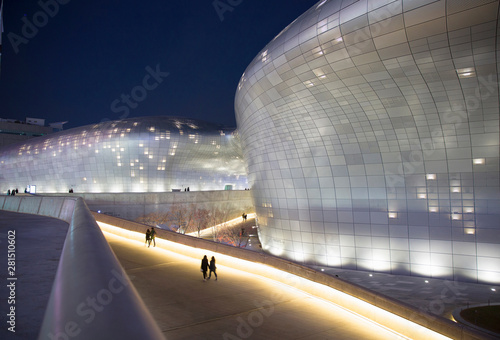 People walking by modern illuminated building at night