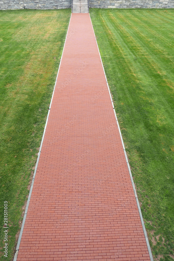 Straight red brick path in a lawn