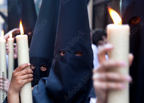 Children in capirote holding lit candles during procession in Spain photo