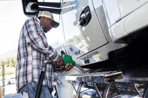 Side view of truck driver filling truck with diesel fuel at truck stop photo