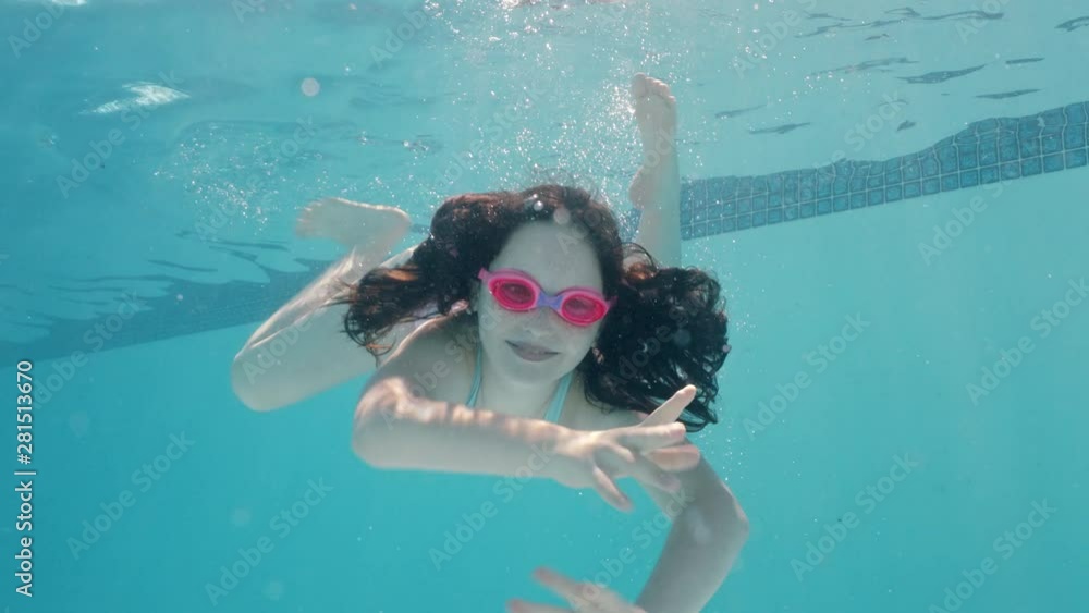 happy girl swimming underwater in pool smiling waving hand enjoying ...