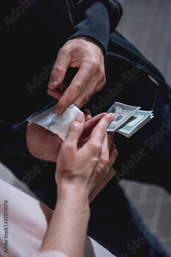 partial view of woman with dollar banknotes buying drugs from thug
