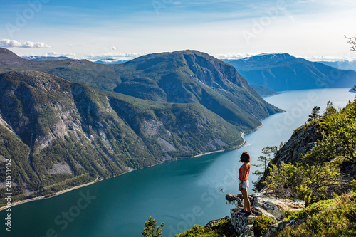 Obraz na płótnie Female traveler enjoying the beautiful scenery at the top of a fjord in Norway during a hike in summer w salonie