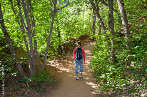 Young girl walking on the Emerald Falls Trail in Zion National Park under a canopy of trees on a summer morning.