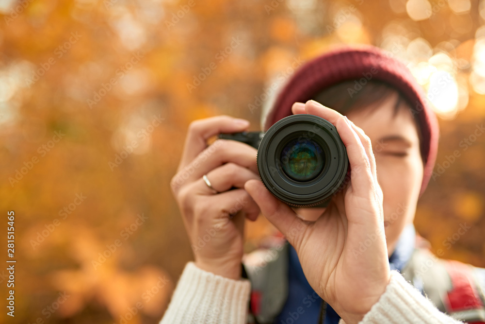 Attractive caucasian girl taking pictures with a mirrorless camera through the forest in the fall in Canada