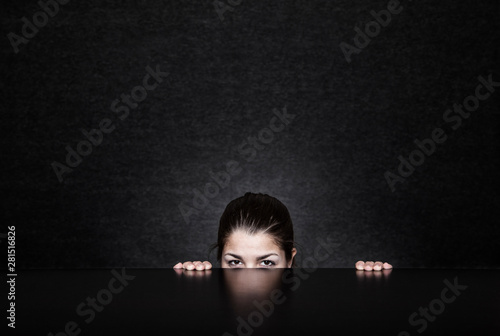 Portrait of woman peeping under the table photo