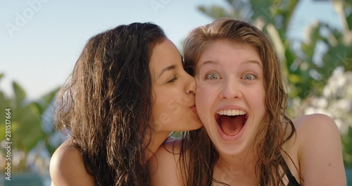 two beautiful women having fun on sunny day woman playfully kissing friend on cheek hugging enjoying summer relaxing together by swimming pool 4k