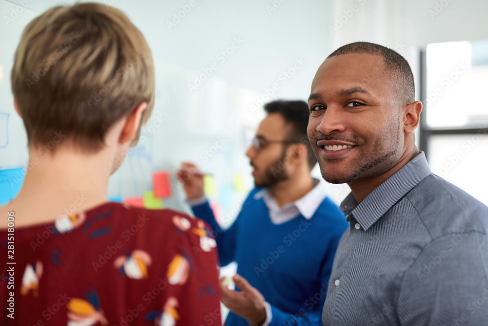 Diverse team of creative millennial coworkers in a startup brainstorming strategies in a positive environment Diverse team of creative millennial coworkers in a startup brainstorming strategies in a positive environment