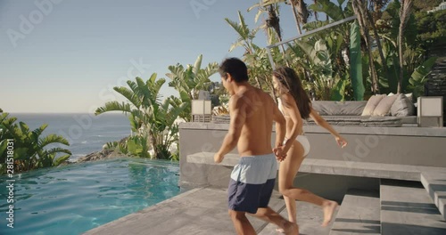 fun couple jumping in swimming pool splashing having fun romantic summer vacation on honeymoon at luxury hotel resort with beautiful ocean view at sunset 4k  photo
