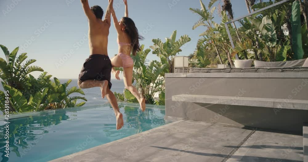 fun couple jumping in swimming pool splashing having fun romantic summer vacation on honeymoon at luxury hotel resort with beautiful ocean view at sunset 4k 
